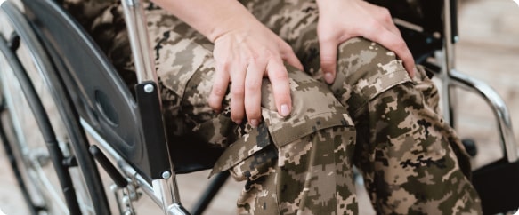 A closeup of a veteran's hands on his lap in a wheelchair