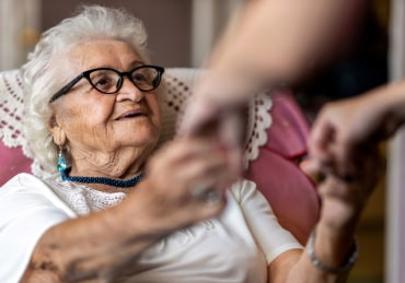 Elderly lady holding hands with caregiver