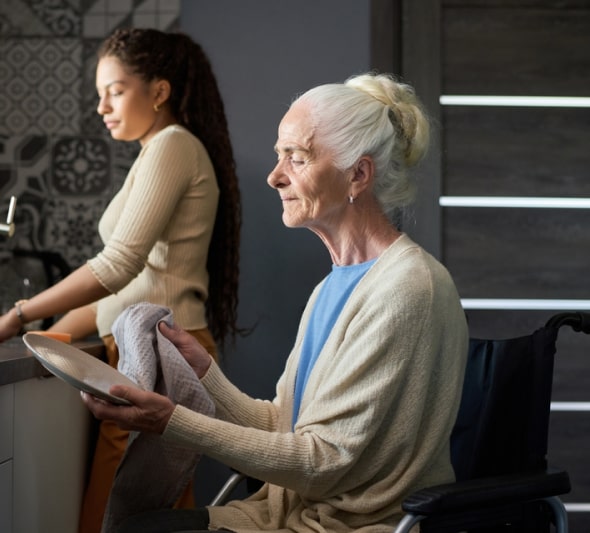 Elderly lady with her caregiver doing dishes together