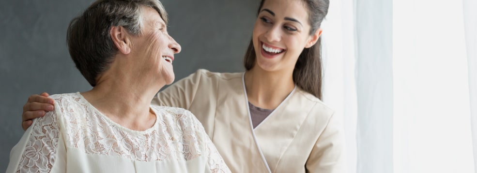 Elderly lady happily spending time with her caregiver